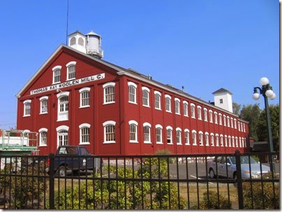 A photo of the Thomas Kay Woolen Mill in Salem, Orebon. This 2.5 story building is red brick with rows of white-trimmed windows.