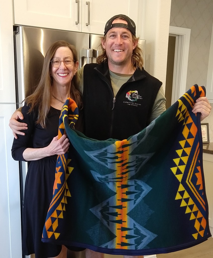 A man and woman stand with a Pendleton Wildland Heroes blanket.