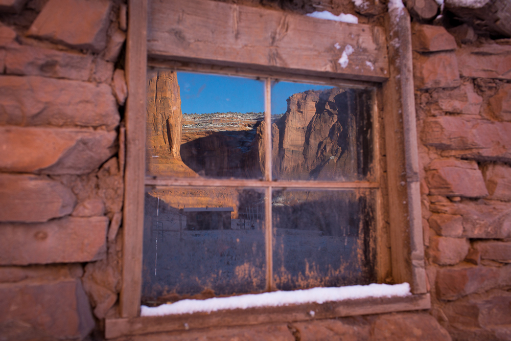 A wondow in a red clay brick home reflects the Canyon de Chelly. 