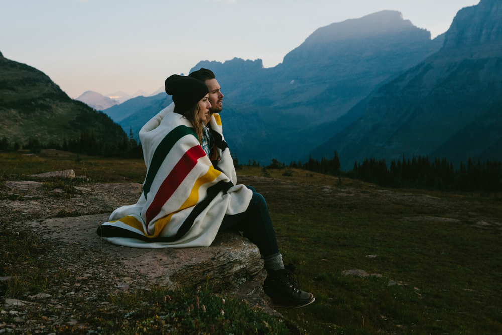 Irey_ A man and woman sit on a rocky outcropping wrapped in a Pendleton Glacier Park blanket