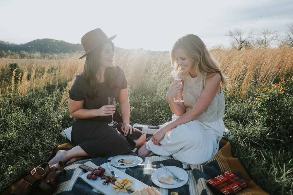 Two women picnic on a Pendleton blanket.