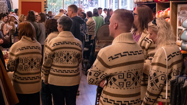 A group of people wearing Westerley sweaters stands waiting to hear the results of a drawing.