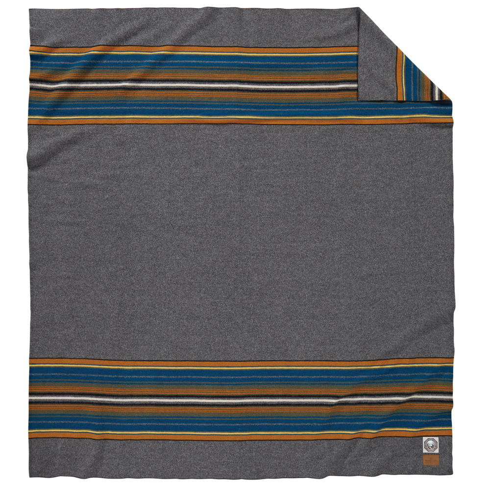 The Olympic National Park blanket by Pendleton. The main part of the blanket is heathered grey with stripes of goldenrod, teal, white and rust at each end.