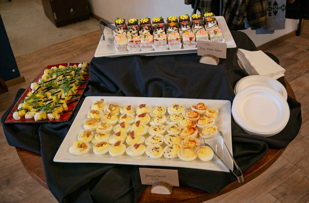 refreshments at party in Pendleton store: deviled eggs, petit fours, fruit skewers, paper plates, serving tongs