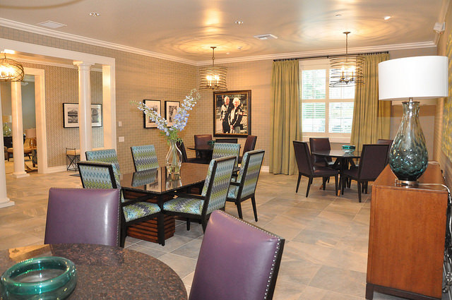 A nicely appointed common room in the Vancouver, Washington Fisher house, with tableds, chairs, lamps, and flower arrangements. 