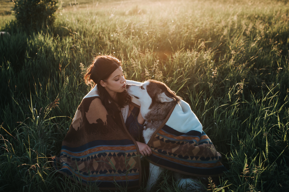 Grace_Adams a young woman wraps her dog in the blanket, and kisses his nose