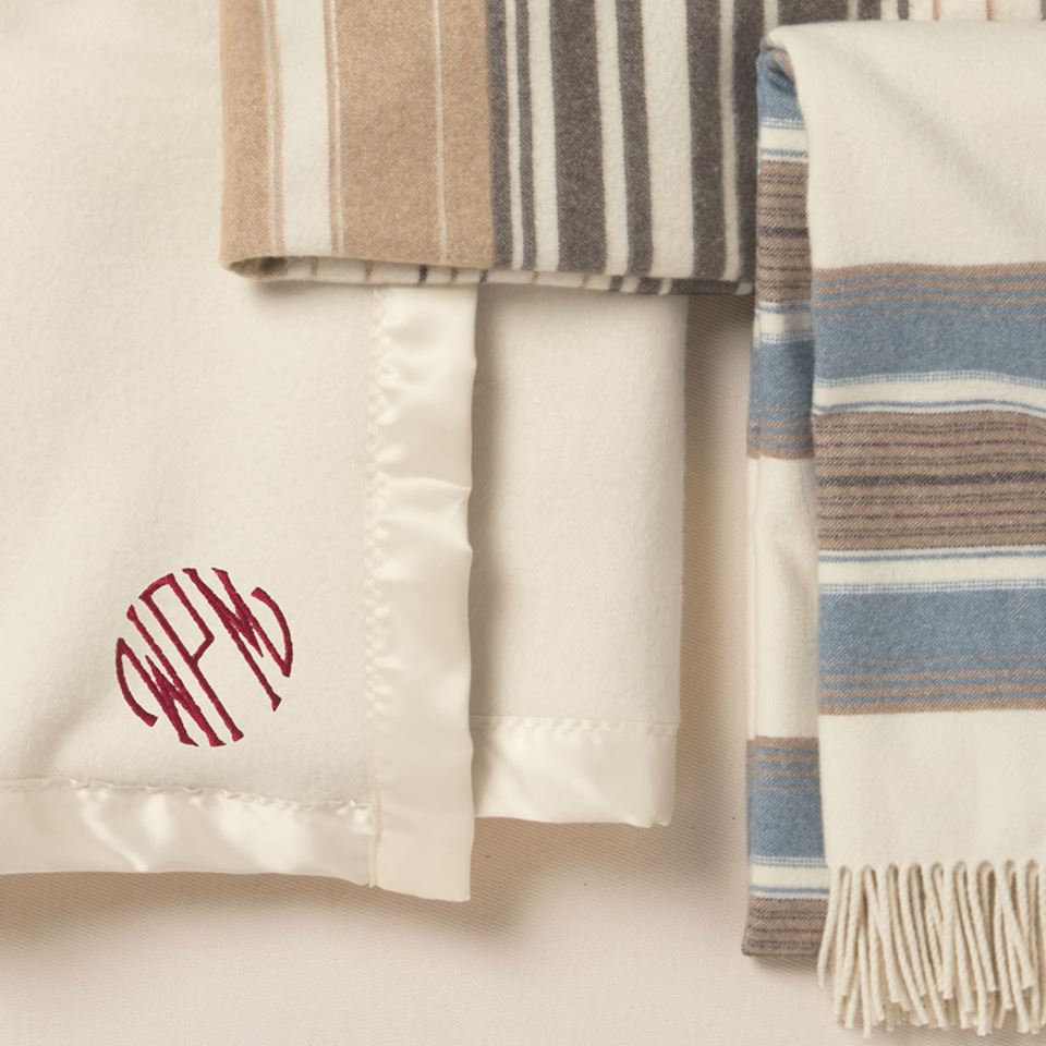 A monogrammed Pendleton bed blanket and two striped throws.