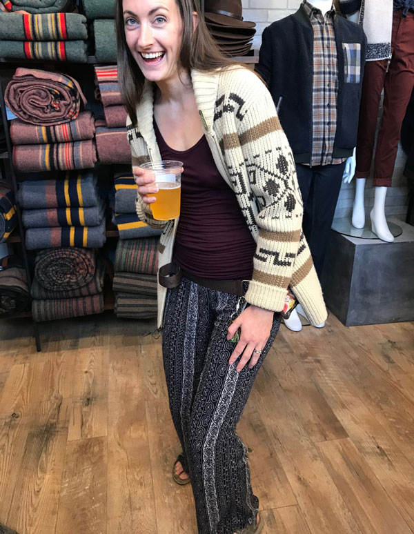 A happy partygoer in a Lebowski sweater enjoys her beer