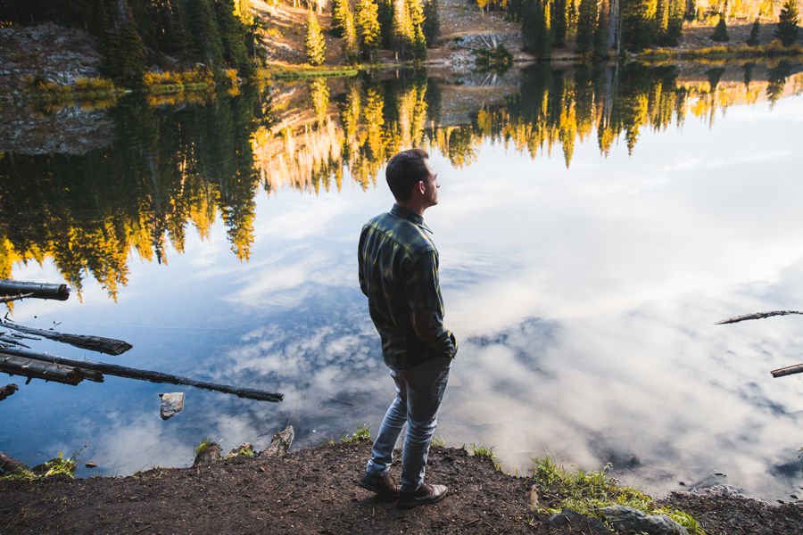 A man stands beside a pond wearing a plaid Pendleton shirt