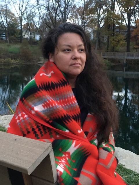 A Native American woman with long, flowing hair stand