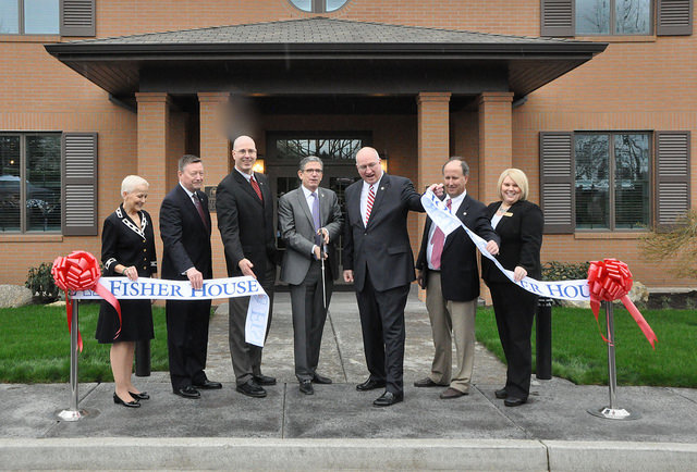 A group of nicely dressed people, inclding representatives of the Fisher House Foundation, and John Bishop, CEO of Pendleton WOolen Mills, participate in a ribbon-cutting to open the new Fisher House in Vancouver, Washington. 