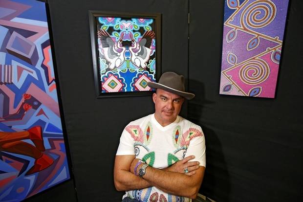 Artist Starr Hardridge at an art show with three of his paintings.