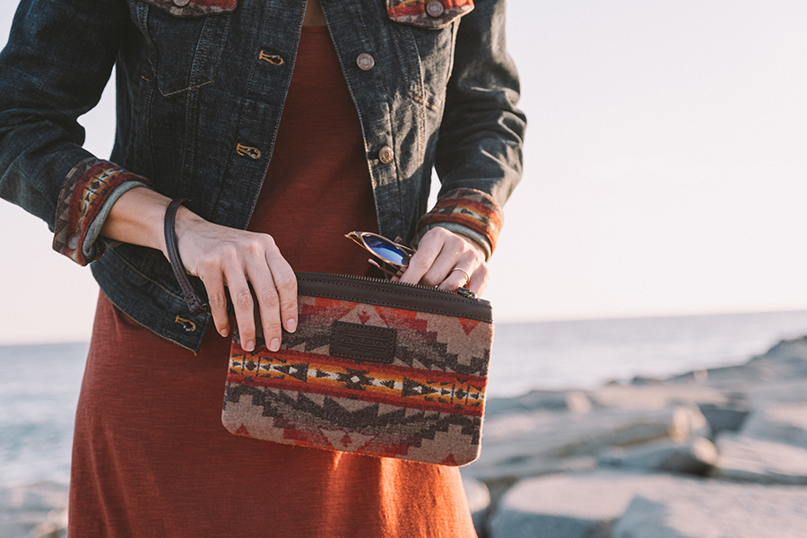 A woman places her sunglasses into her Sierra Ridge bag.