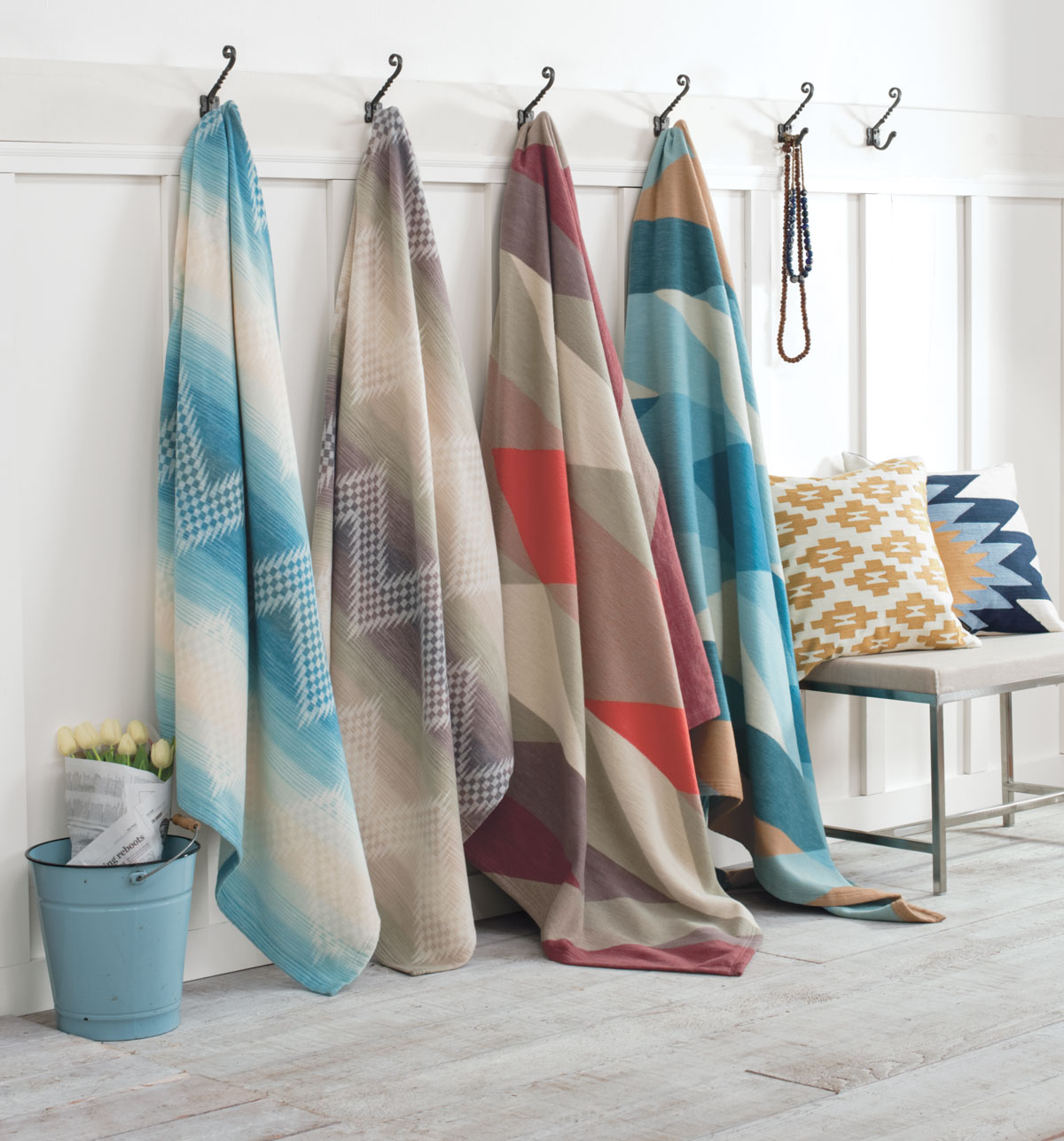 Pendleton cotton bed blankets hanging from hooks against a white wall