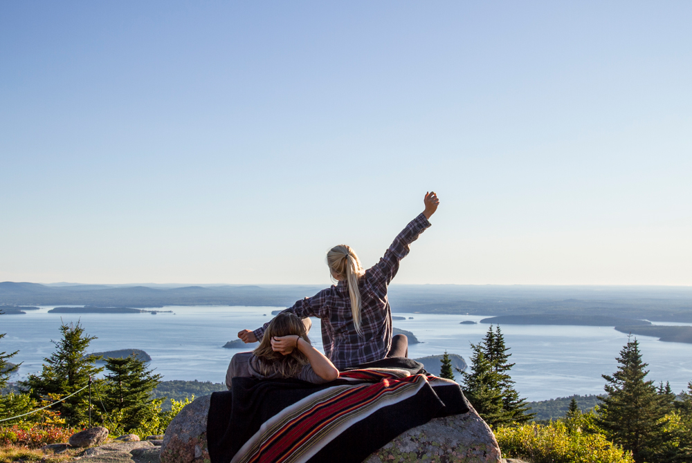 Okoniewski-2 women sit on a boulder with the Pendleton Acadia park blanket.