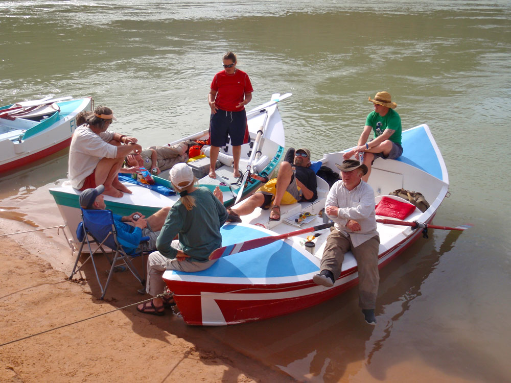 Greg Hatten and five friends relax on and around two wooden boats on the banks of the Colorado River.