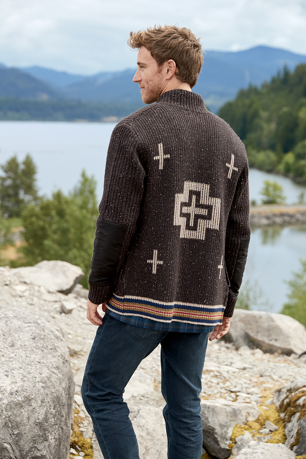 man wearing brown pendleton cardigan standing in front of lake