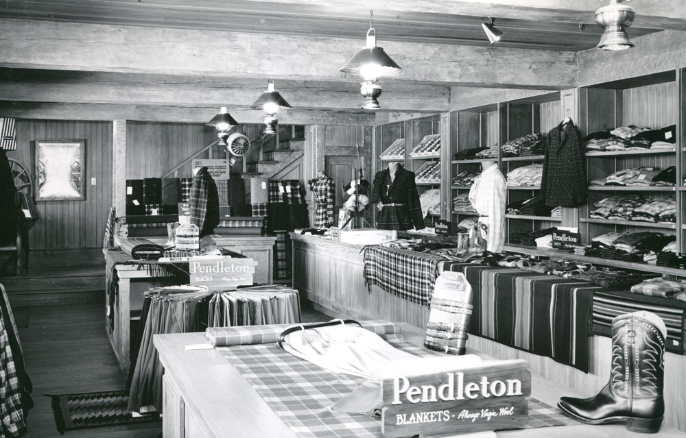 A photo from the Pendleton archives of the Pendleton store in Disneyland: Blanket counter and shirt shelves, with stairway to second floor