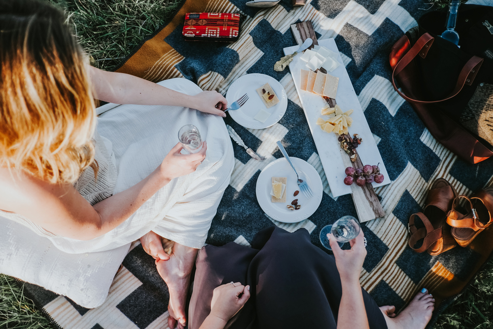 Two women picnic on a Pendleton blanket. 