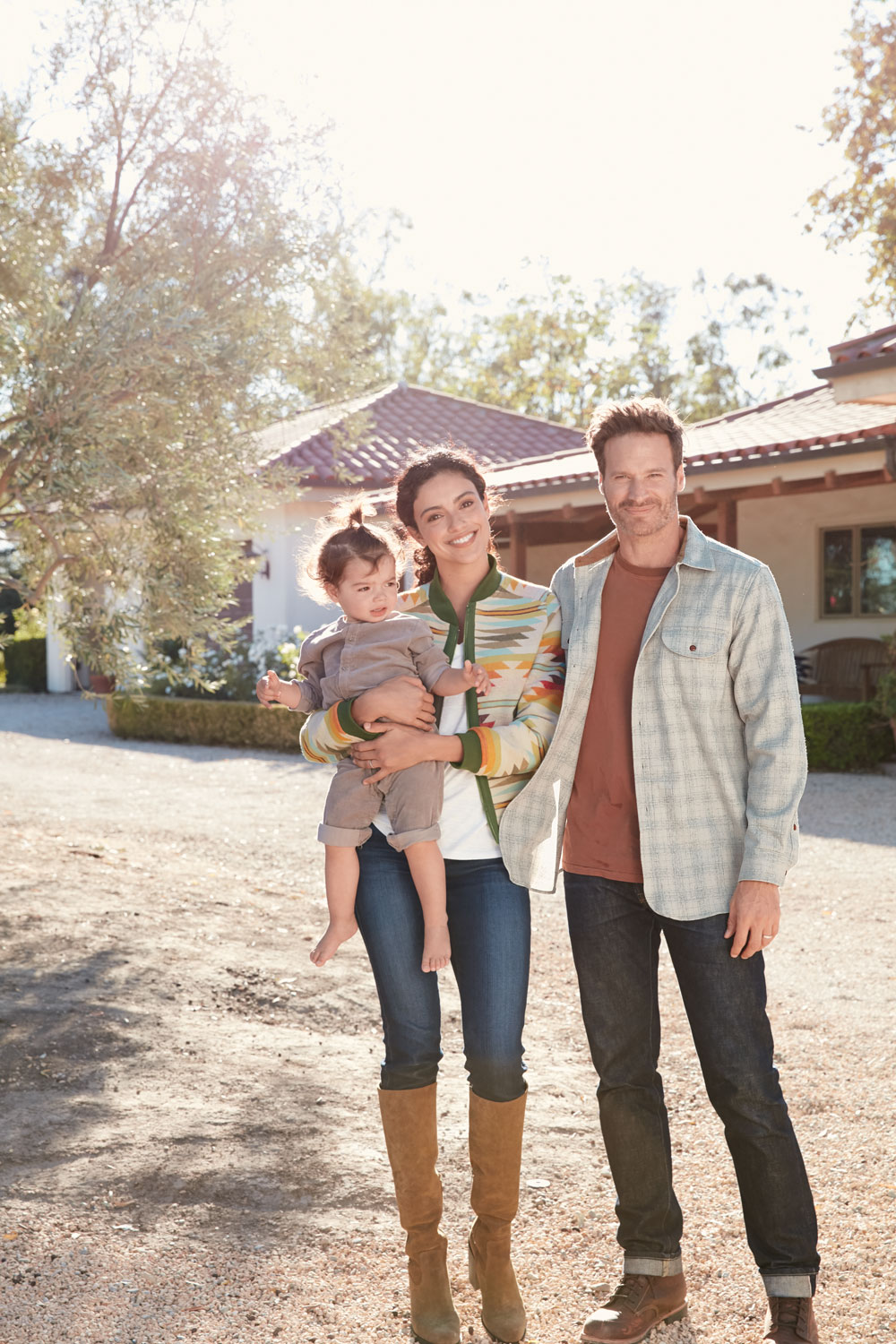 A man, woman and child stand in a driveway, she is wearing a Falcon Cove patterned jacket