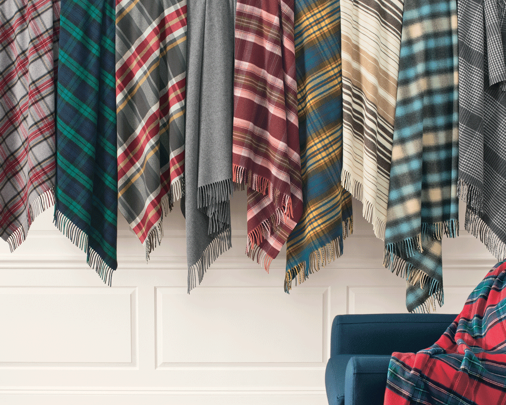 A row of Pendleton Fifthe Avenue throws hang on pegs.