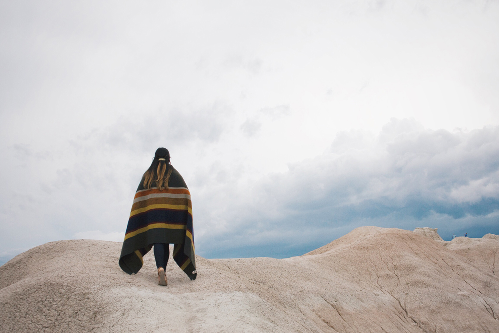 a woman wrapped in a blanket walks on a rock formation