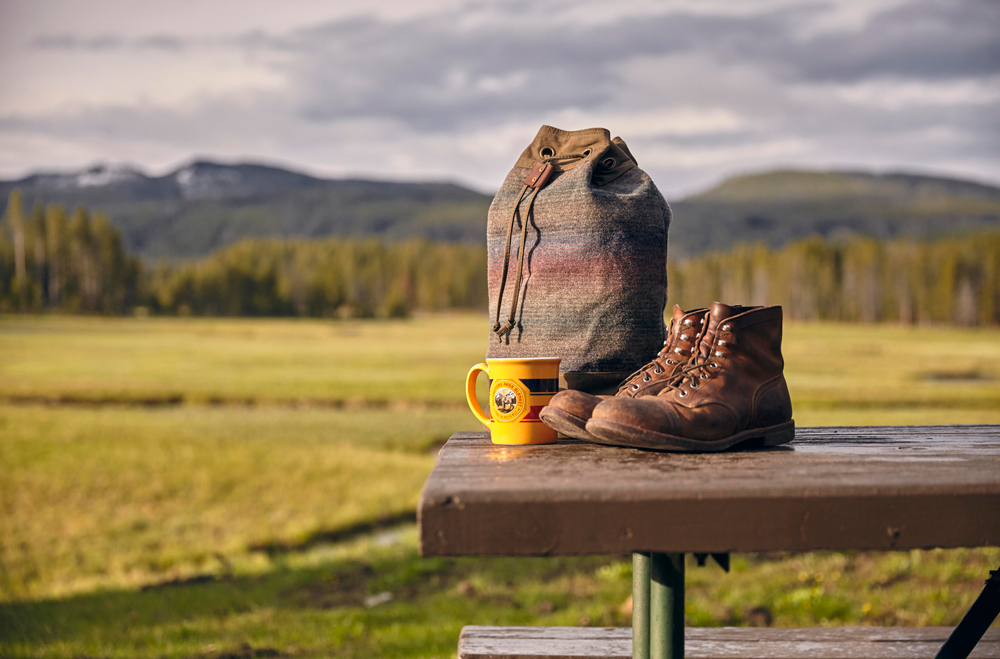 OurFreeWays_ Bag, boots, coffee cup on a picnic table