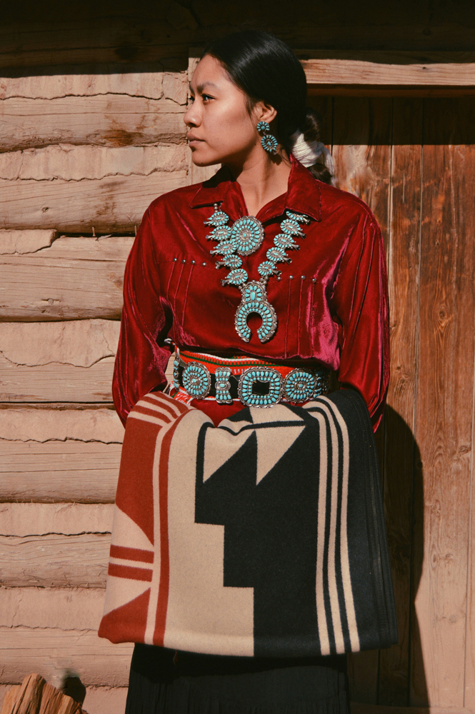 Shondina Lee Yikasbaa poses in traditional Dine clothing, family jewelry, and the Gift of the Earth blanket. 