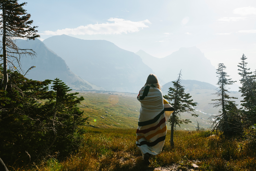 Irey_ A woman wrapped in a Pendleton blanket looks at glaciers in Glacier natioal Park