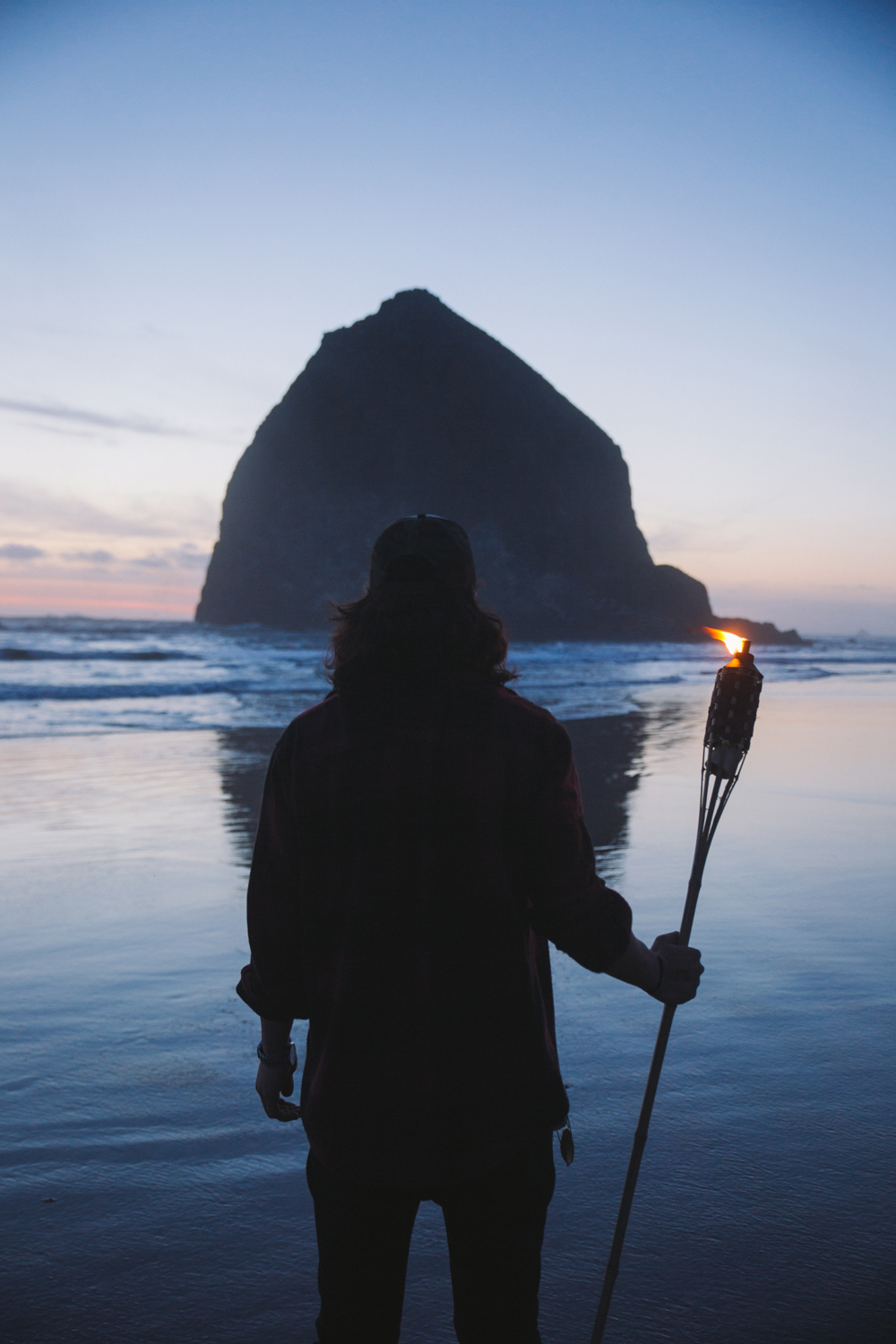 A man in silhouette in front of Haystack Rock