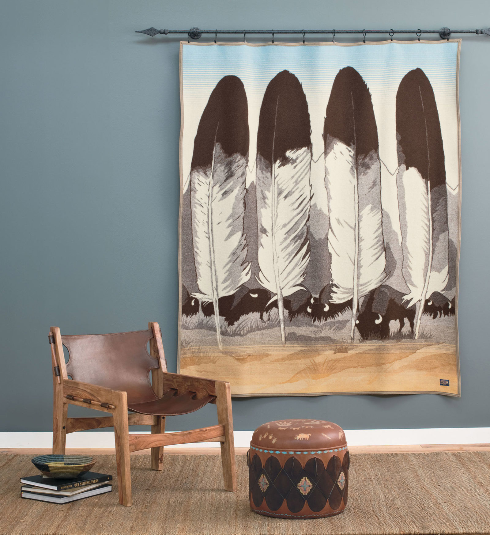 On the wall hangs the Pendleton Legendary Series blanket, "In Their Element" designed by artist Joe Toledo. The blanket design contains four eagle feather, a mountain range, and a herd of grazing buffalo.