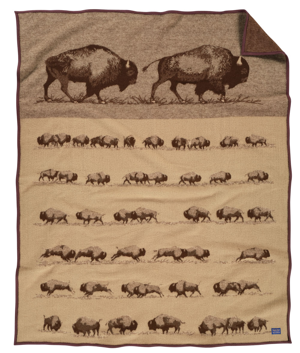 The "Buffalo Roam" blanket by Pendleton Woolen Mills, from a work of art by Joe Toledo. At the top of the blanket, two large buffalo travel to the right. Below them, six rows of smaller buffalo are shown. Mr. Toledo's buffalo studies show the strength and agility of this massive animal.