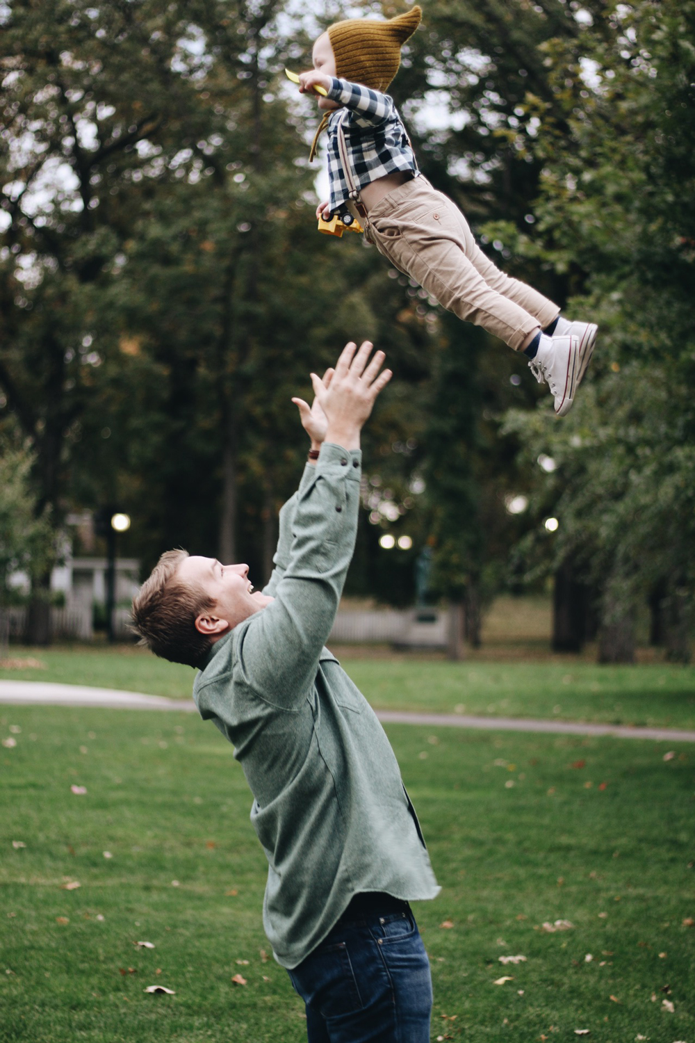 A man tosses his young child into the air with joy. Photo by Bri Heiligenthal