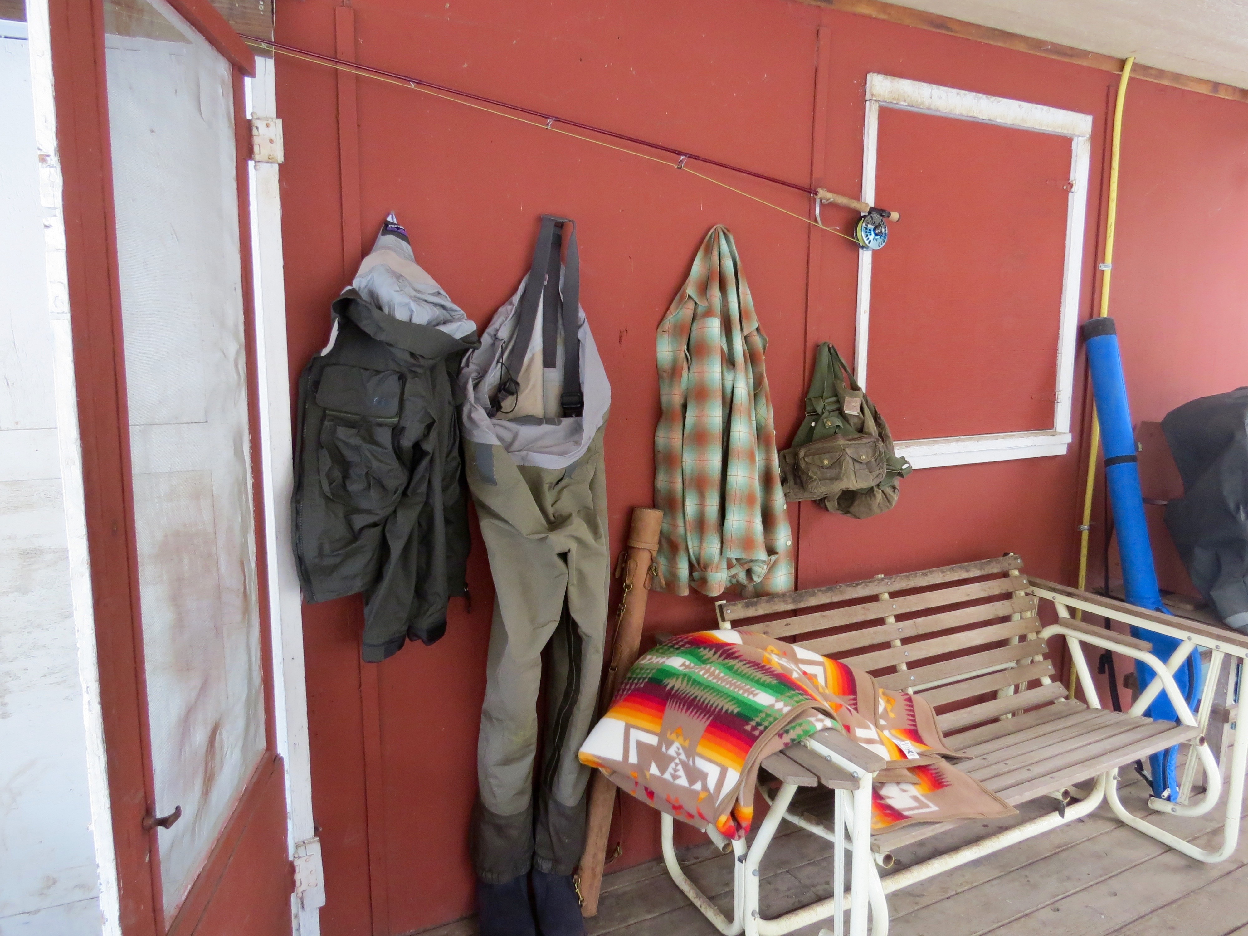 Wadrers, a wool shirt, and a Pendleton blanket on the front porch of a cabin.