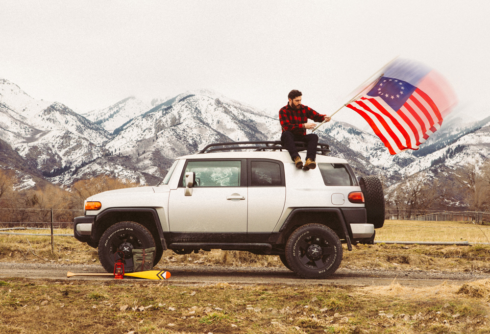 Brandon Burk photogrpahy - a man on a white SUV with an American flag