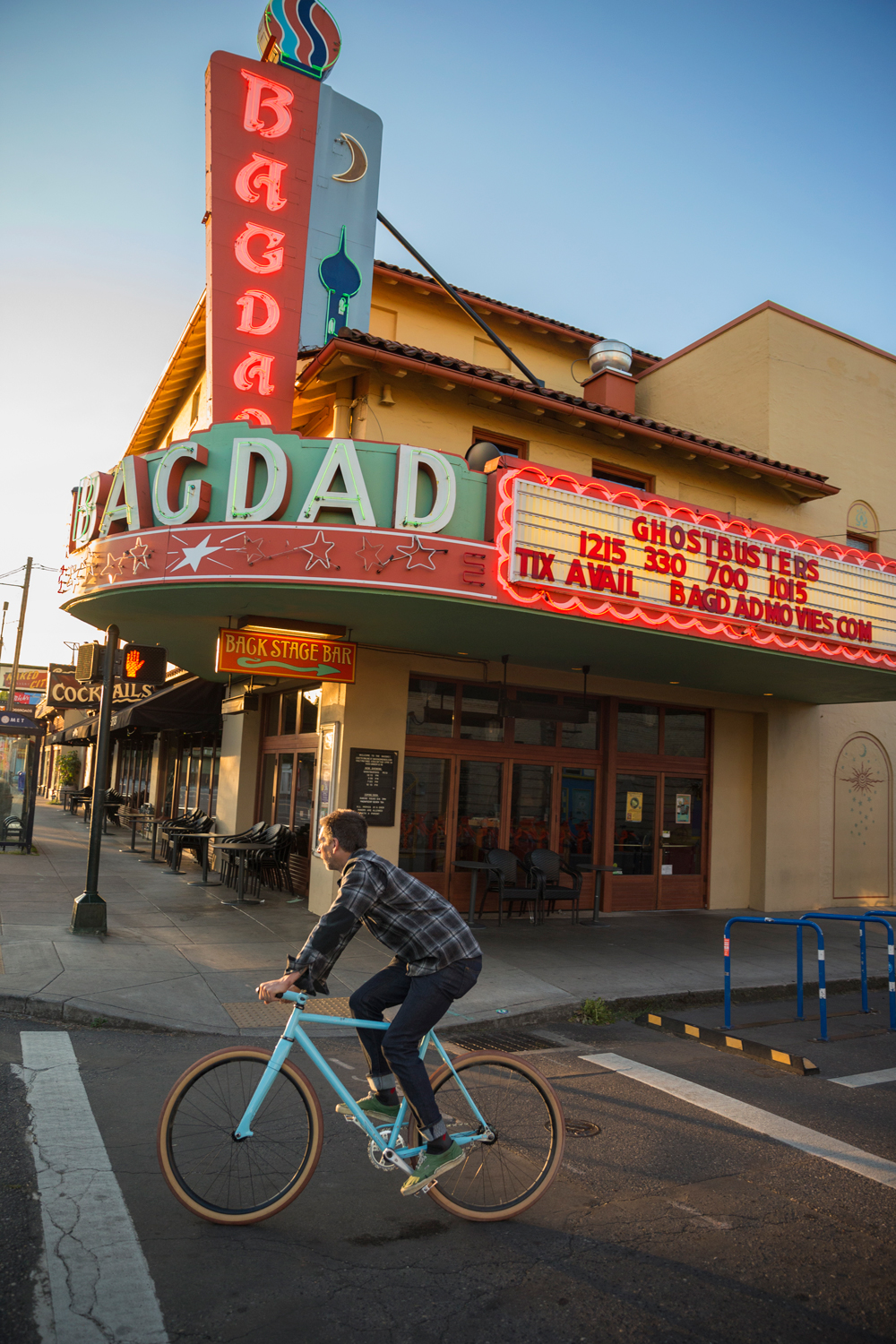 man riding bike in front of Portland's Baghdad movie theater