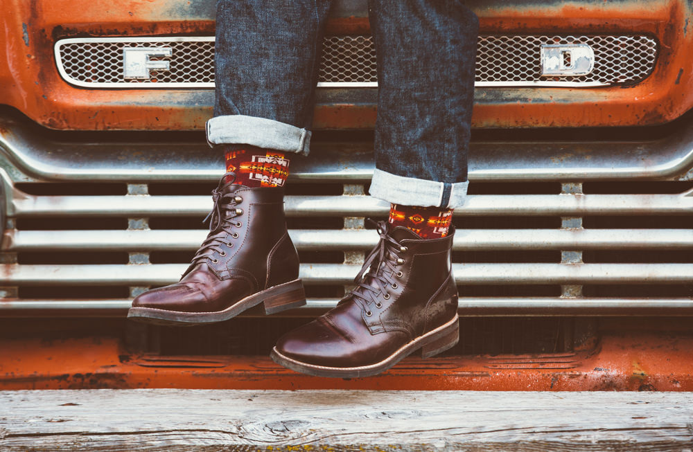 Brandon-Burk-Photography: a photo of a man's feet in boots and Pendleton socks, in front of a car grill. 