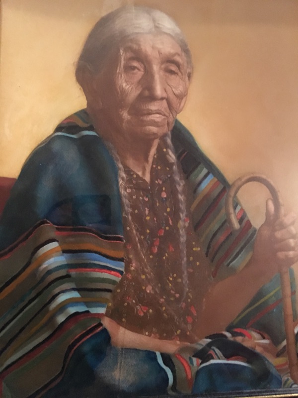 A painting of a Native American matriarch wearing a striped Pendleton blanket. Artist unknown.