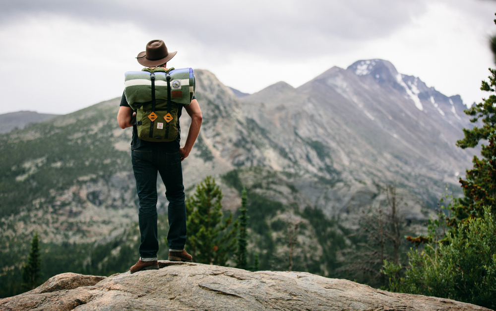 Kate Rolston photo of a man with a pack standing on a mountaintop. 