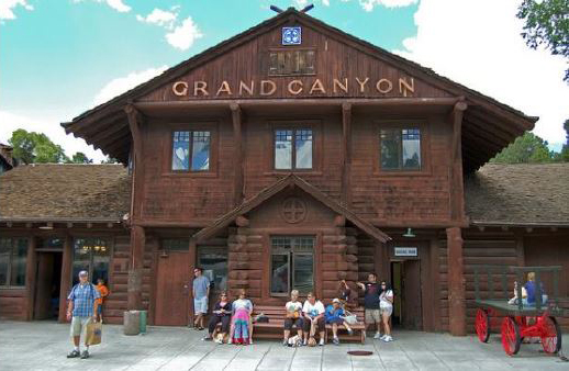 A color photo of the exterior of the Grand Canyon Train Depot. A historic log building with the words "Grand Canyon" on the front gable.