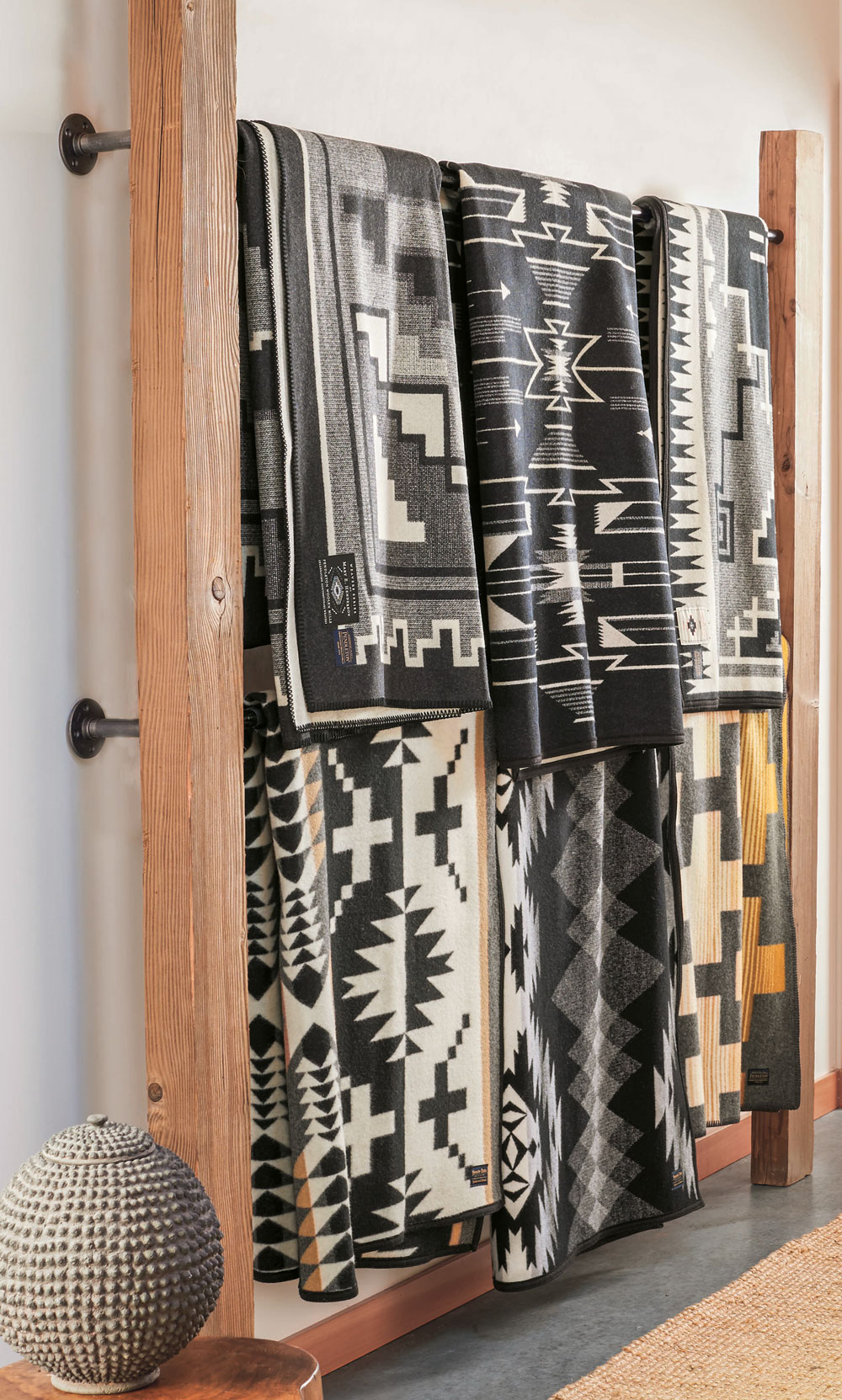 Six black and white Pendleton blankets, displayed on a wall mounted rack.