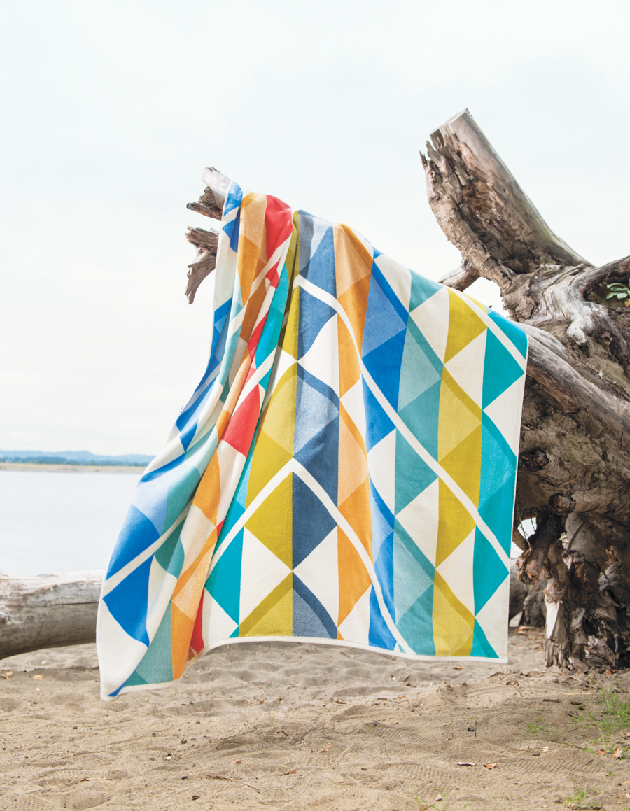 The Serrado towel-for-two hangs on a stump at the beach.