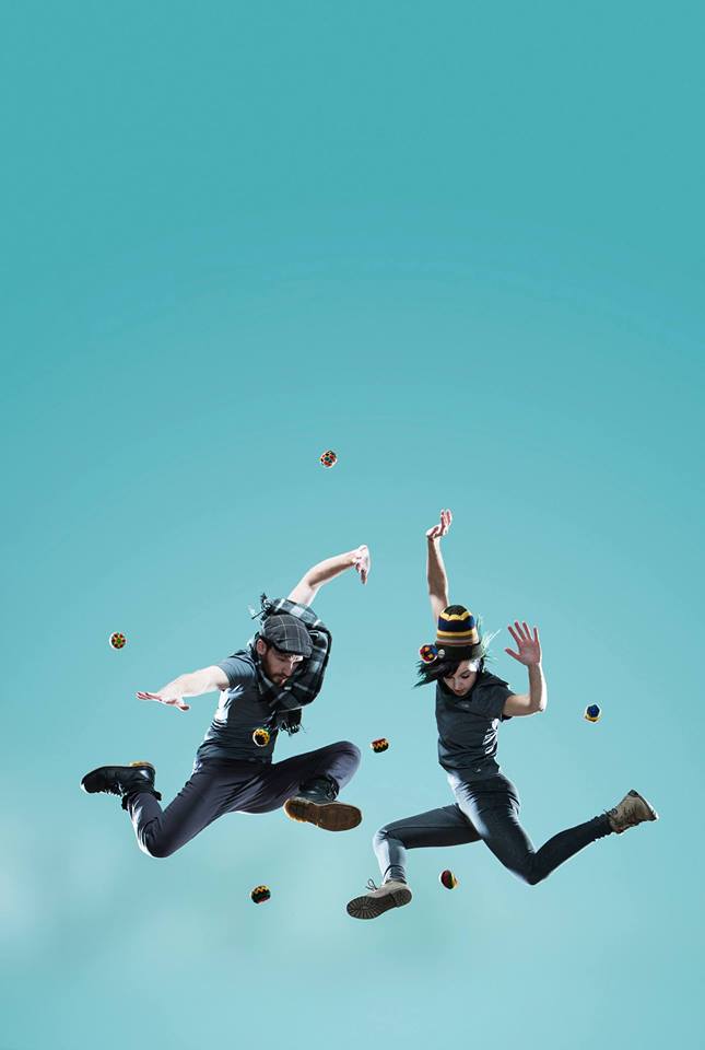 Two BodyVox dancers leap in the air surrounded by hackysacks.