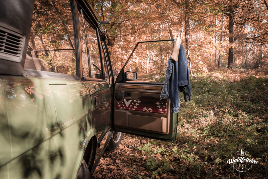 A denim jacket hangs on a car door.