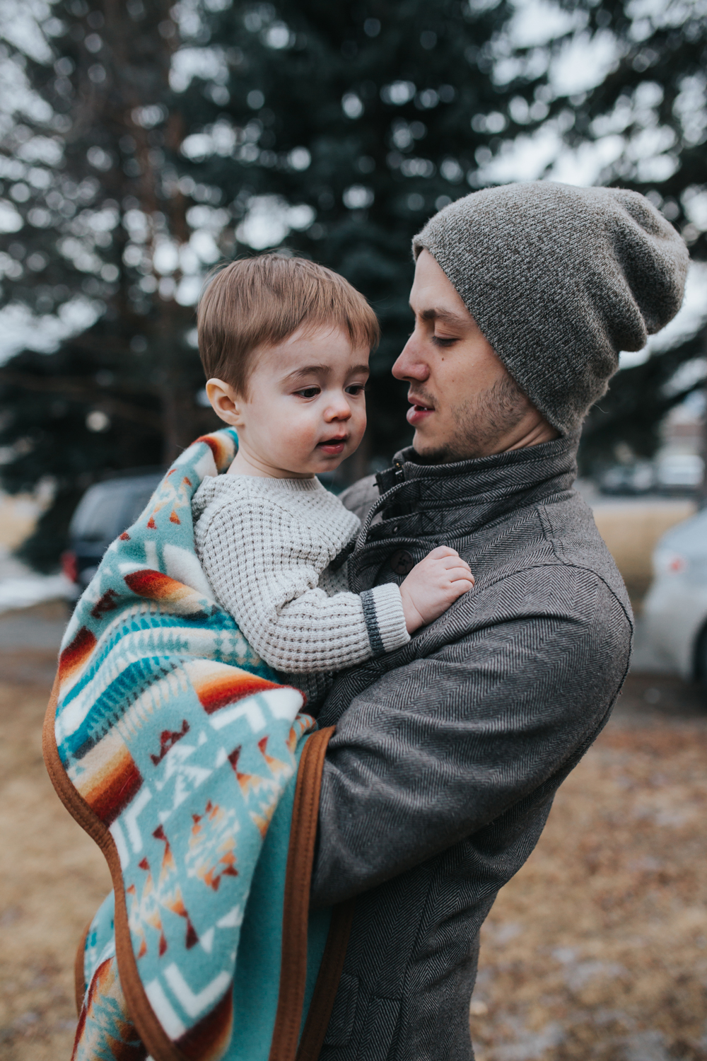 A young father holds his child, who is wrapped in a Pendleton child's blanket. Photo by Grace Adams