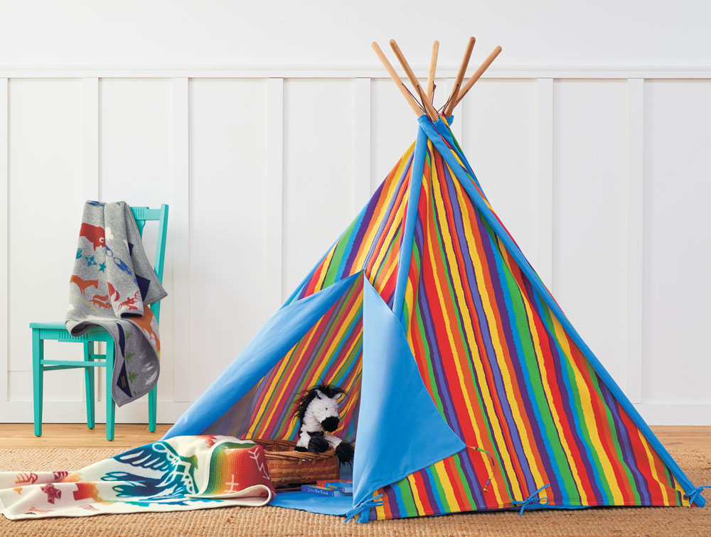 A colorful play tent in bold strips holds toys and a Pendleton Sunrise Eagle child's blanket.