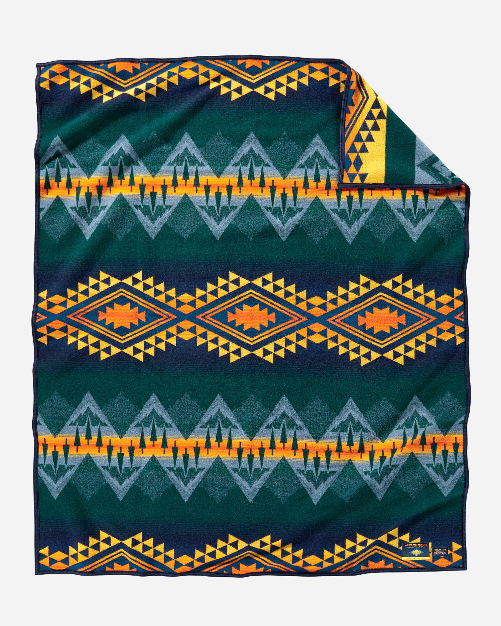 The Pendleton Wildland Heroes blanket shows bands of geometric designs that also include evergreen trees, with a dark forest green background, light blue trangles to symbolize water, and yellow and orange accents that represent the threat of wildfires.