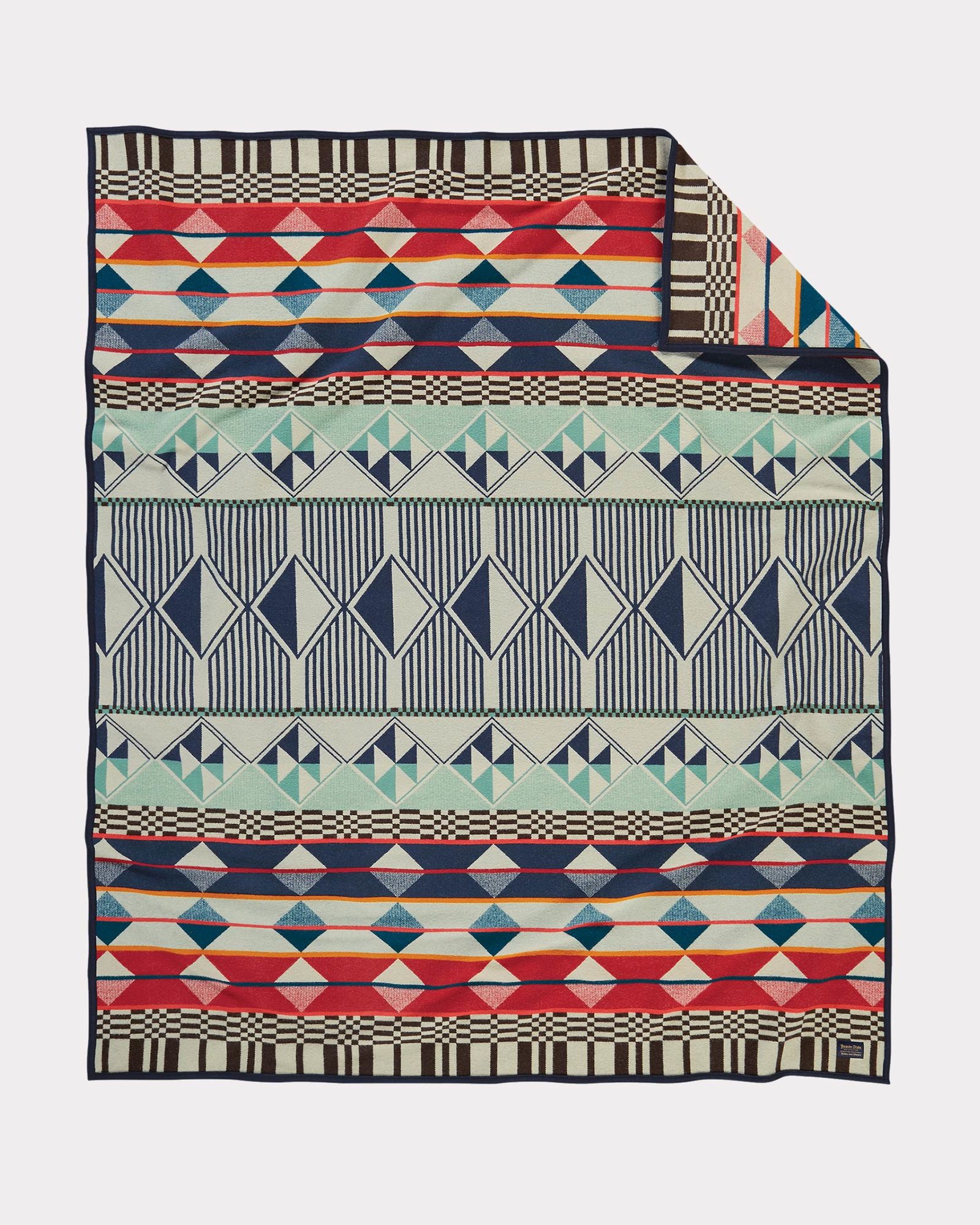 The Southern Highlands blanket by Pendleton is a geometric pattern in pale green, navy blue, rust red and beige.