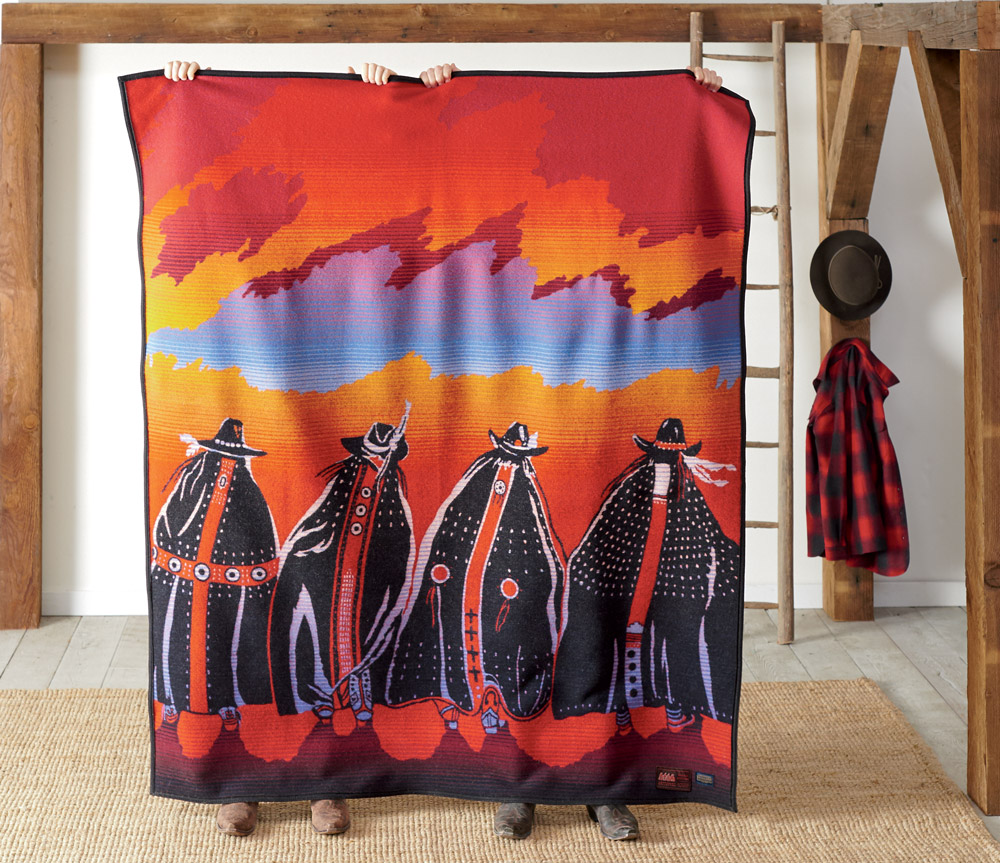 Pendleton Legendary Series blanket, Rodeo Sisters, held up by two people standing behind it.